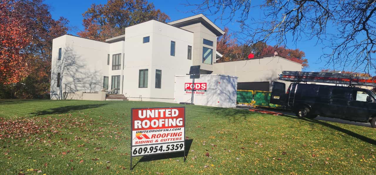 A modern two-story home with a United Roofing sign in the yard. A work van is parked nearby.