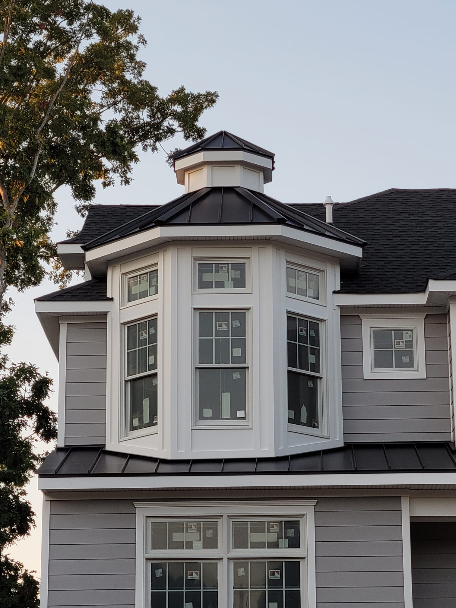Gray house exterior with white trim, octagonal turret and black roof.