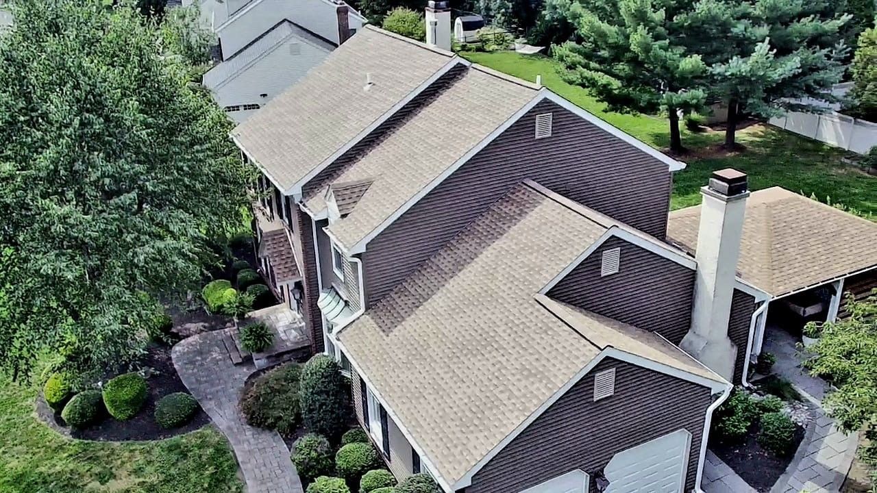 Aerial view of a brown-sided house with a light brown roof and a green yard.