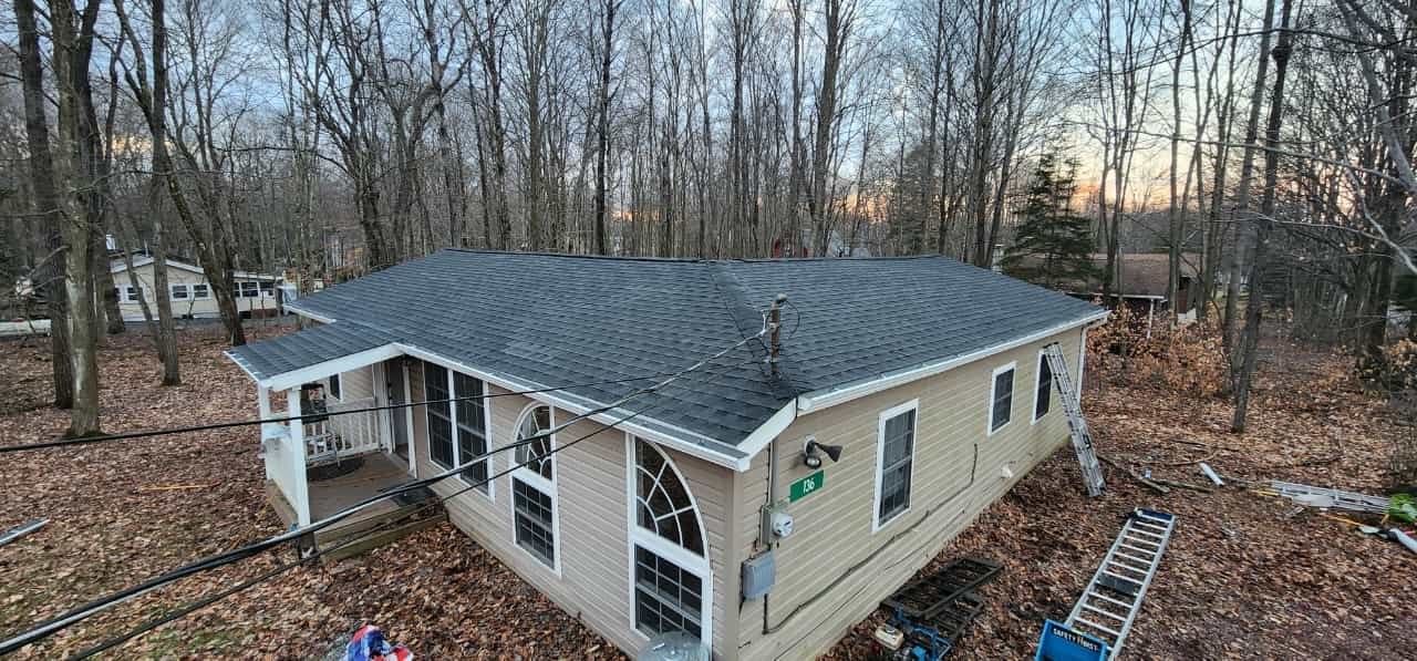 A house with a dark gray roof surrounded by trees in a wooded area.