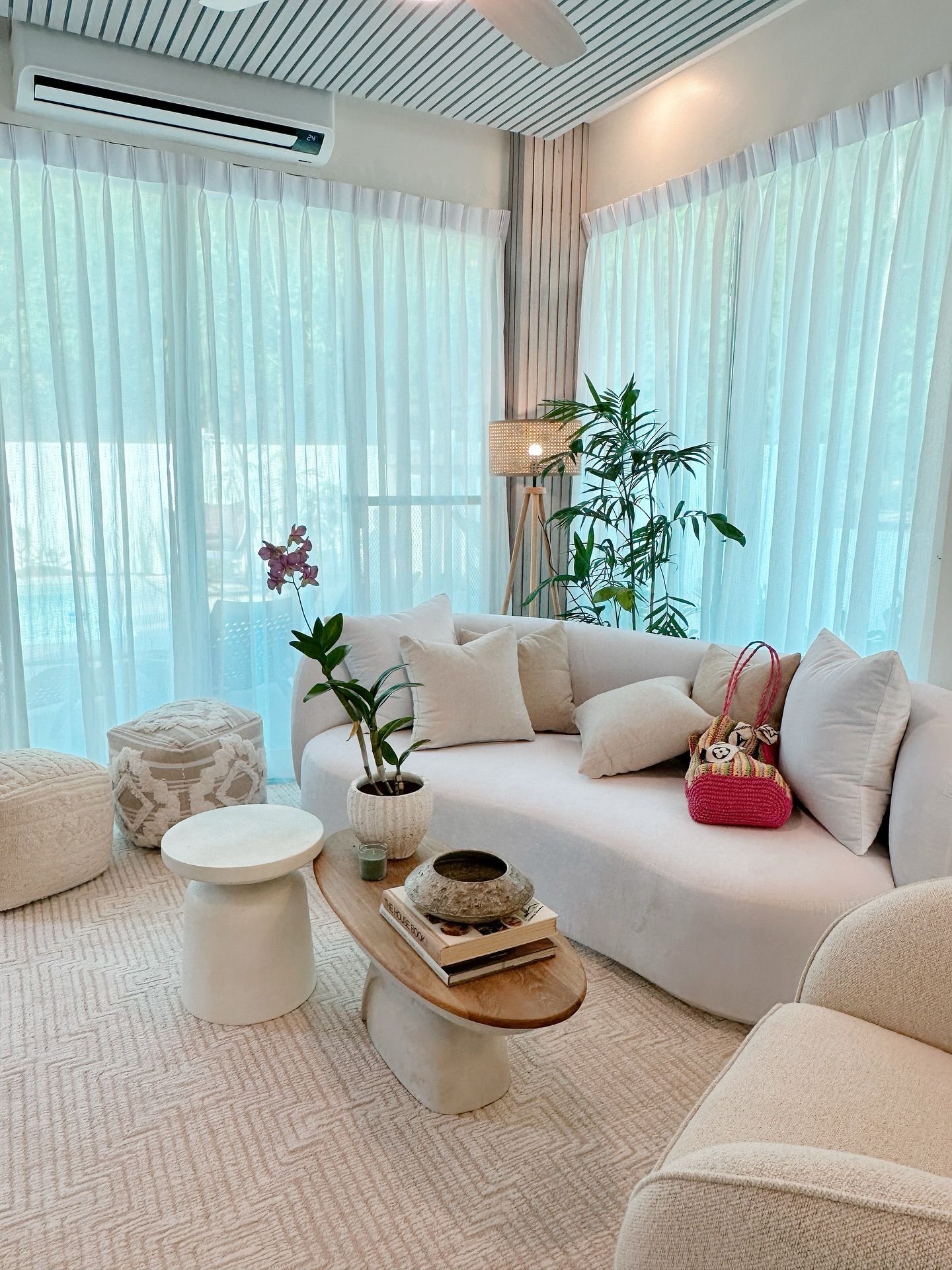 Bright living room with curved cream sofa, white curtains, and a wooden coffee table.