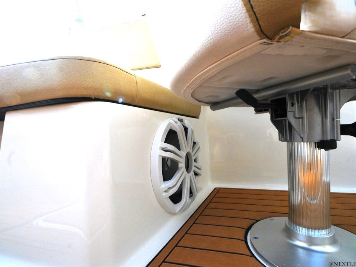 Under-seat view of a white boat interior with a speaker and metal table leg on a wooden floor