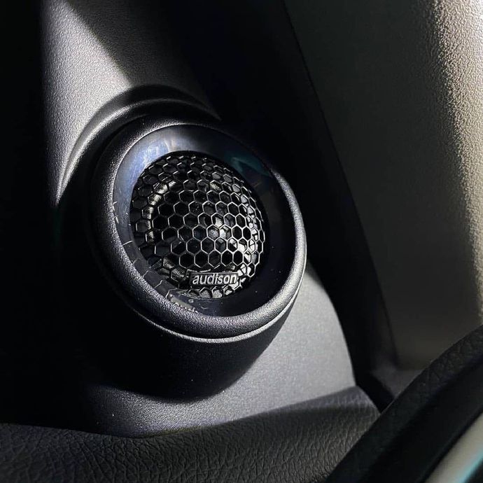 Close-up of a car dashboard tweeter speaker with a honeycomb grille