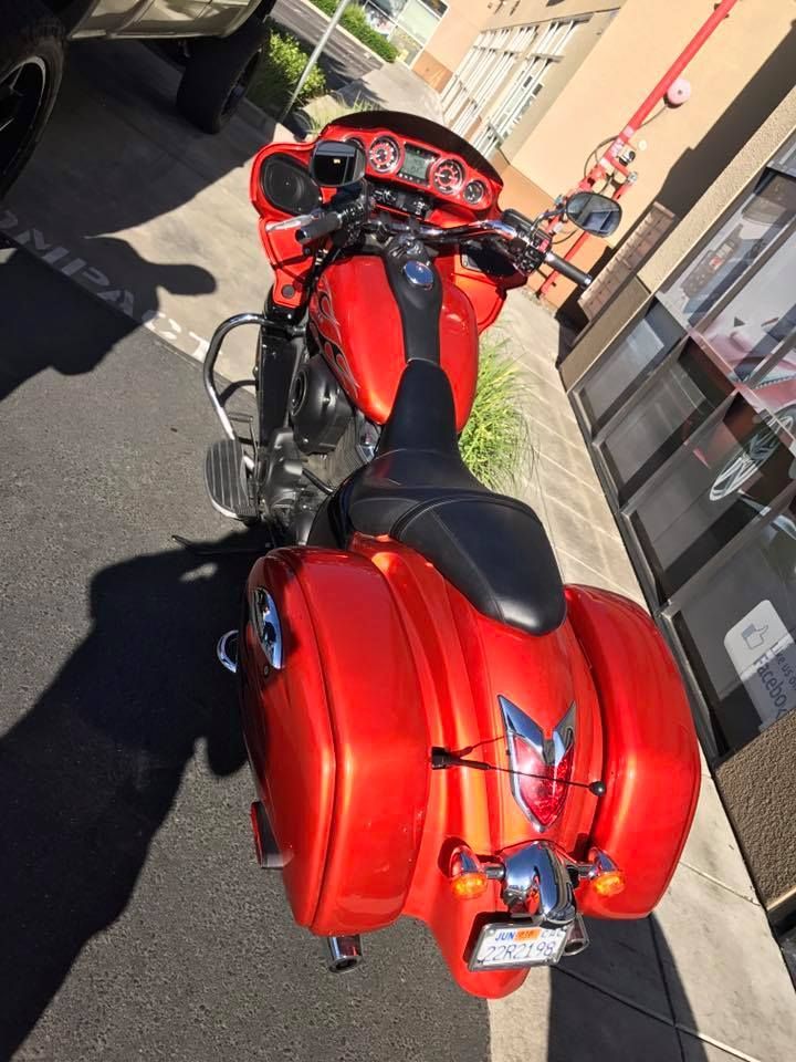Red motorcycle parked on a sidewalk beside a building, viewed from above