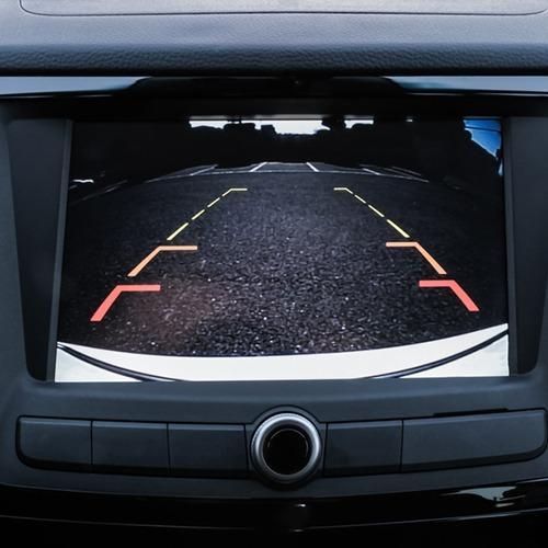 Car dashboard display showing a rearview camera view of the road with parking guide lines