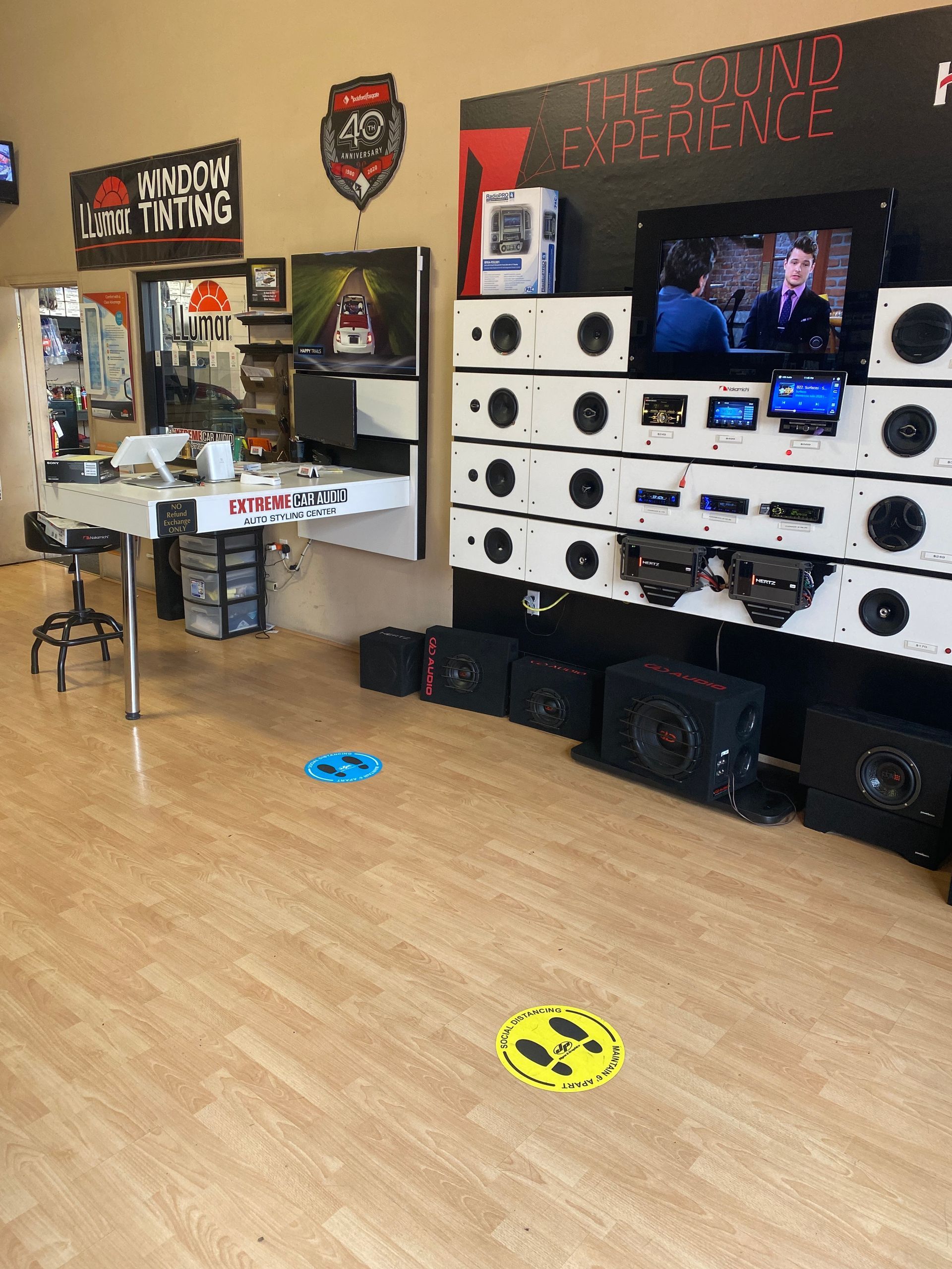 Indoor arcade training area with a TV, stacked targets, and colorful floor markers on a wood floor