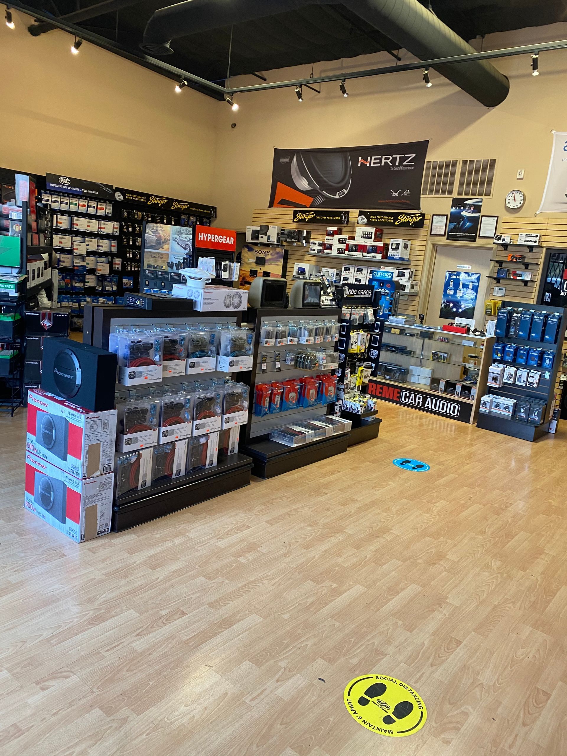 Retail store aisle with shelves of boxed electronics and accessories on a light wood floor.