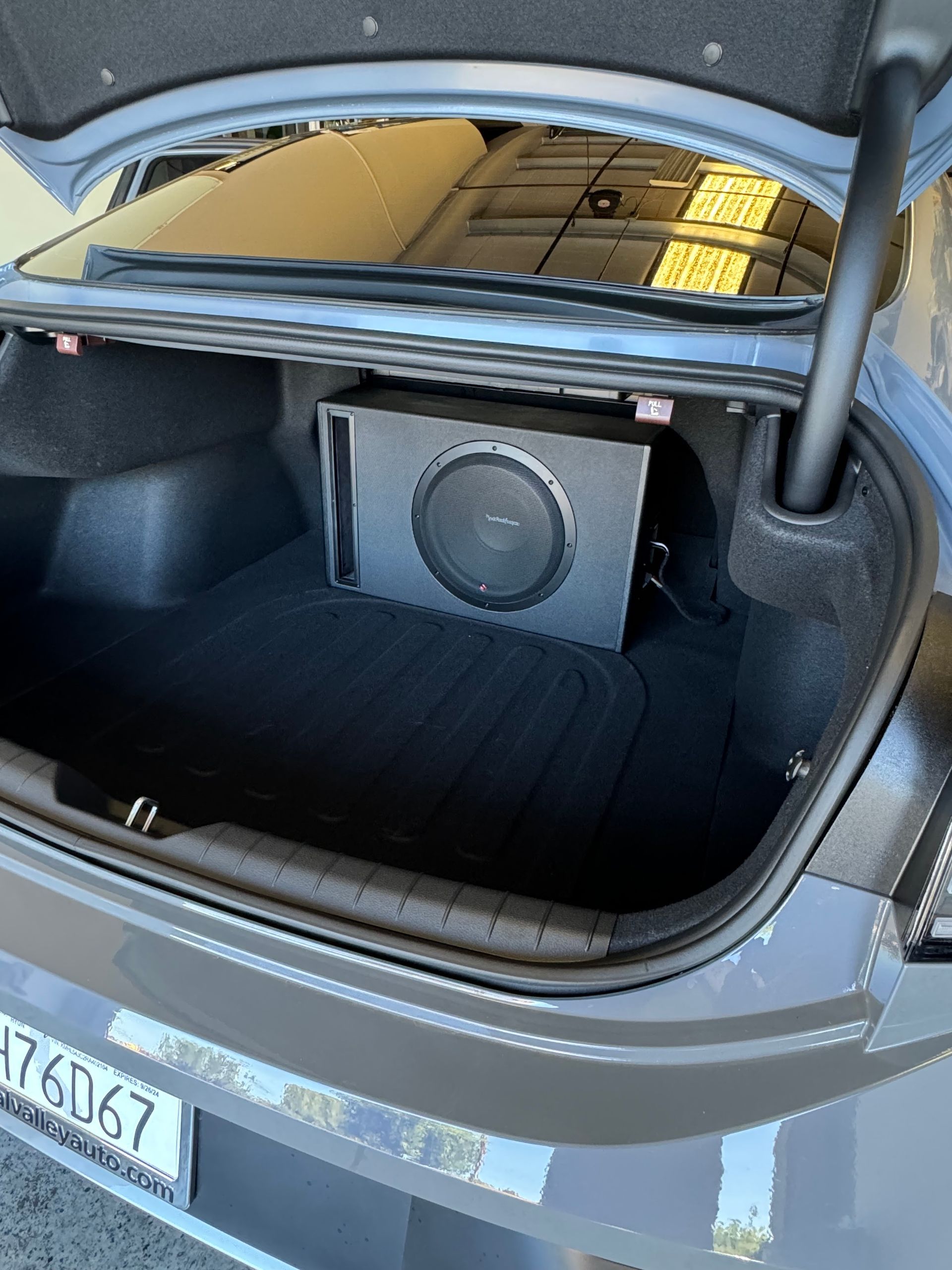 Open car trunk with a subwoofer box installed in the cargo area.