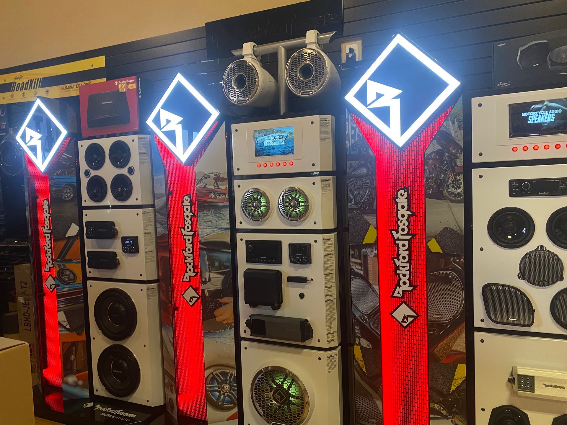 Custom car audio display with lit speaker towers and red panels in a showroom