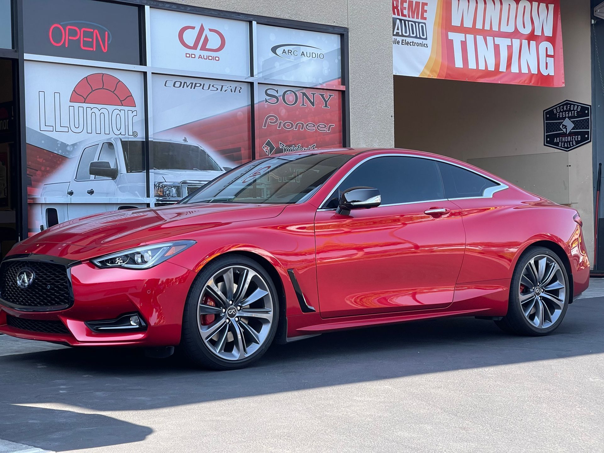 Red sports coupe parked outside a window tinting shop