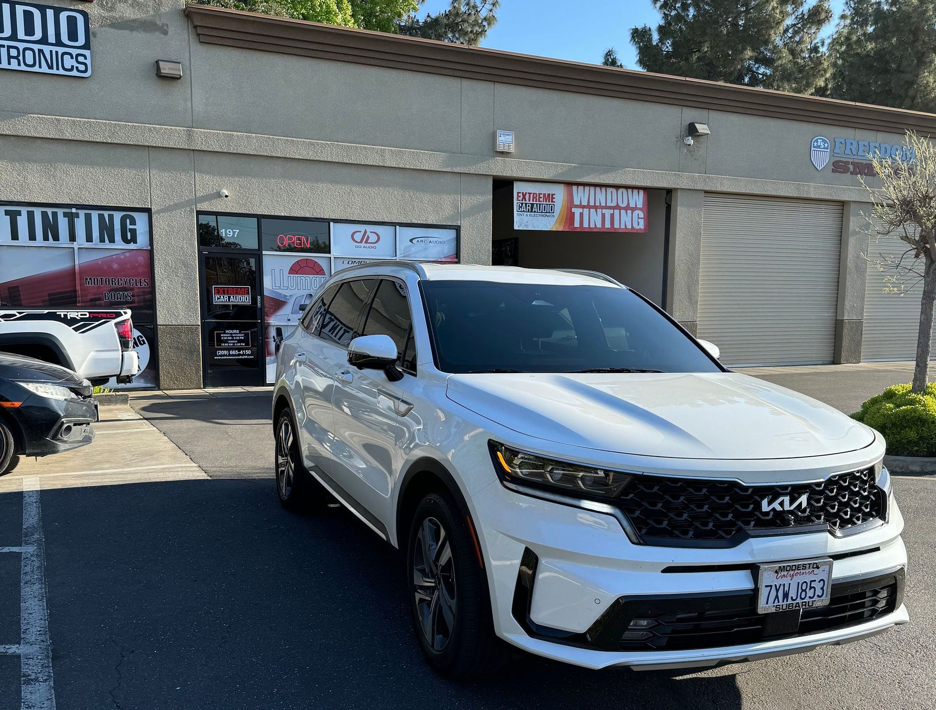White SUV parked outside a tire shop on a sunny day