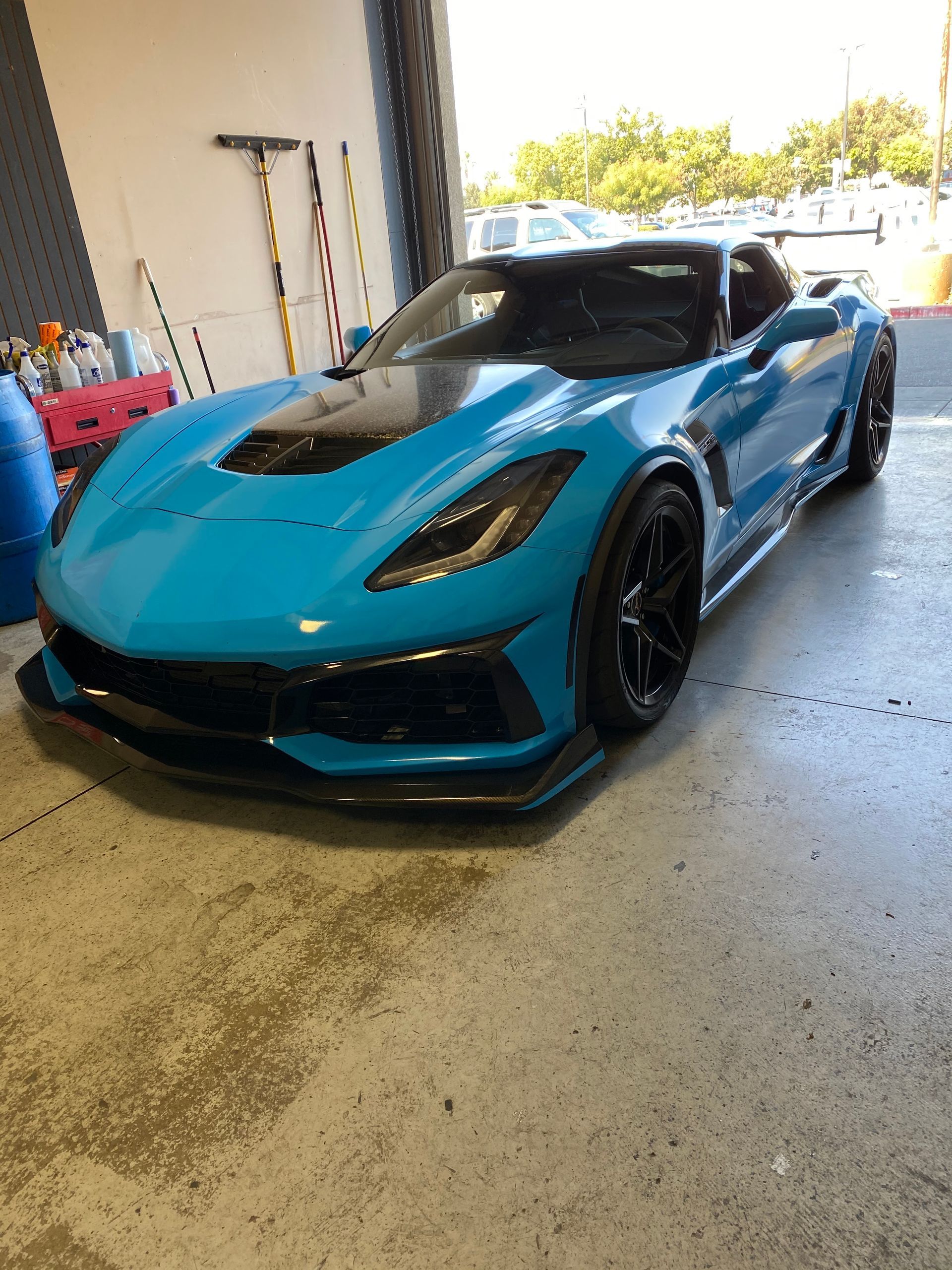Blue sports car parked inside a garage, viewed from the front-left side.