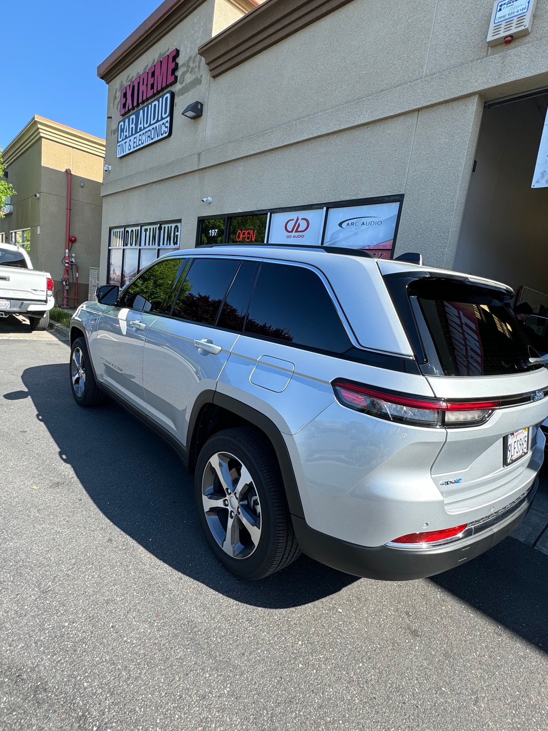 Silver SUV parked beside a strip mall building on a sunny day