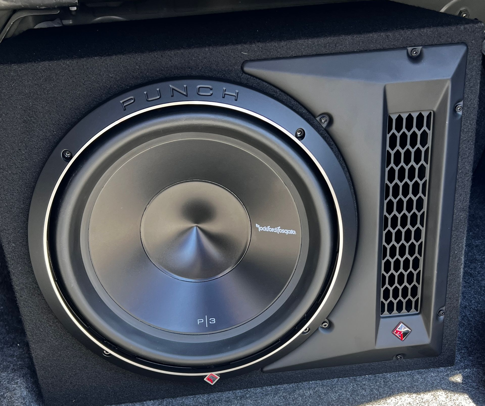 Black Rockford Fosgate subwoofer in a car trunk enclosure with a vented side panel