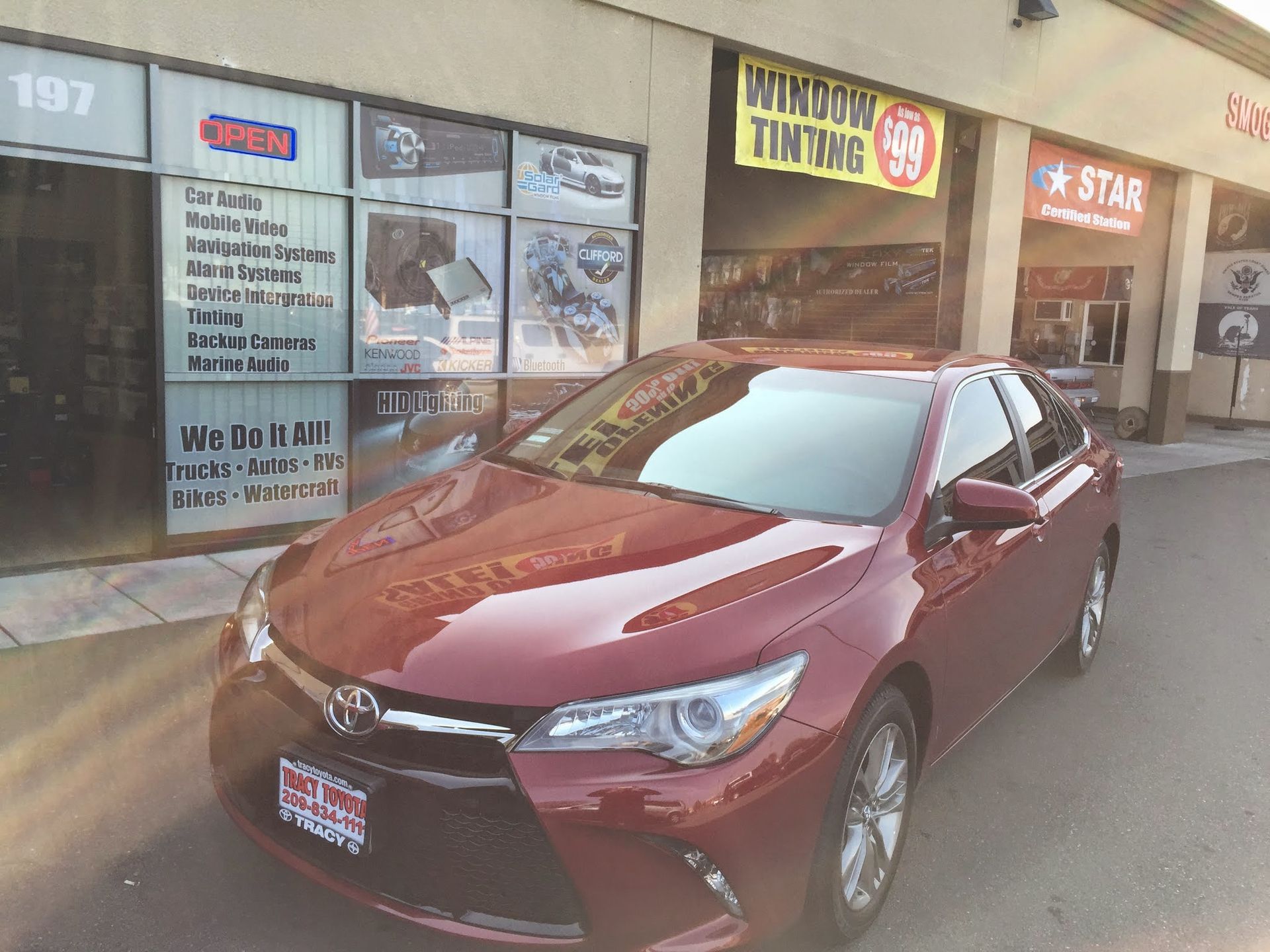 Maroon sedan parked outside a storefront with window signs and wet pavement
