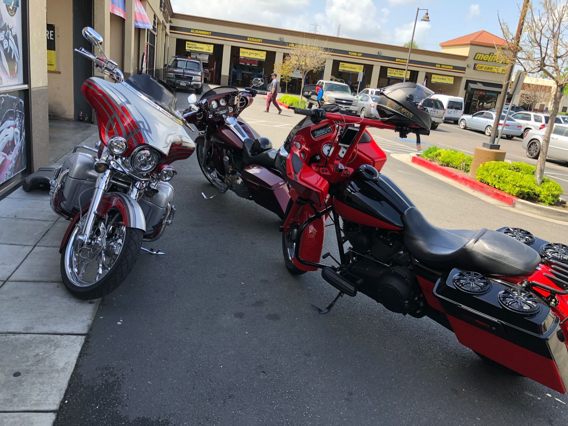 Two red motorcycles parked on a street near a storefront and sidewalk.