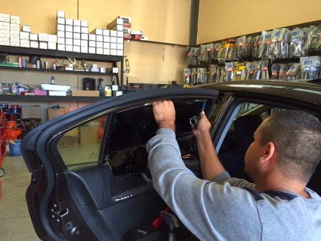Man installing a car stereo inside a vehicle in an auto repair shop