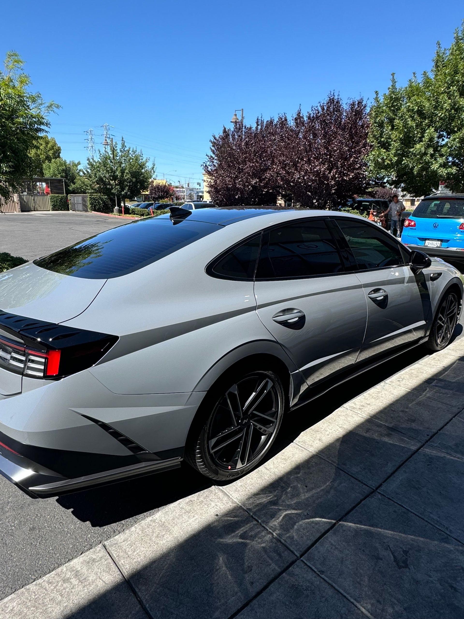 Silver sports sedan parked in a sunny lot with black rims and tinted windows