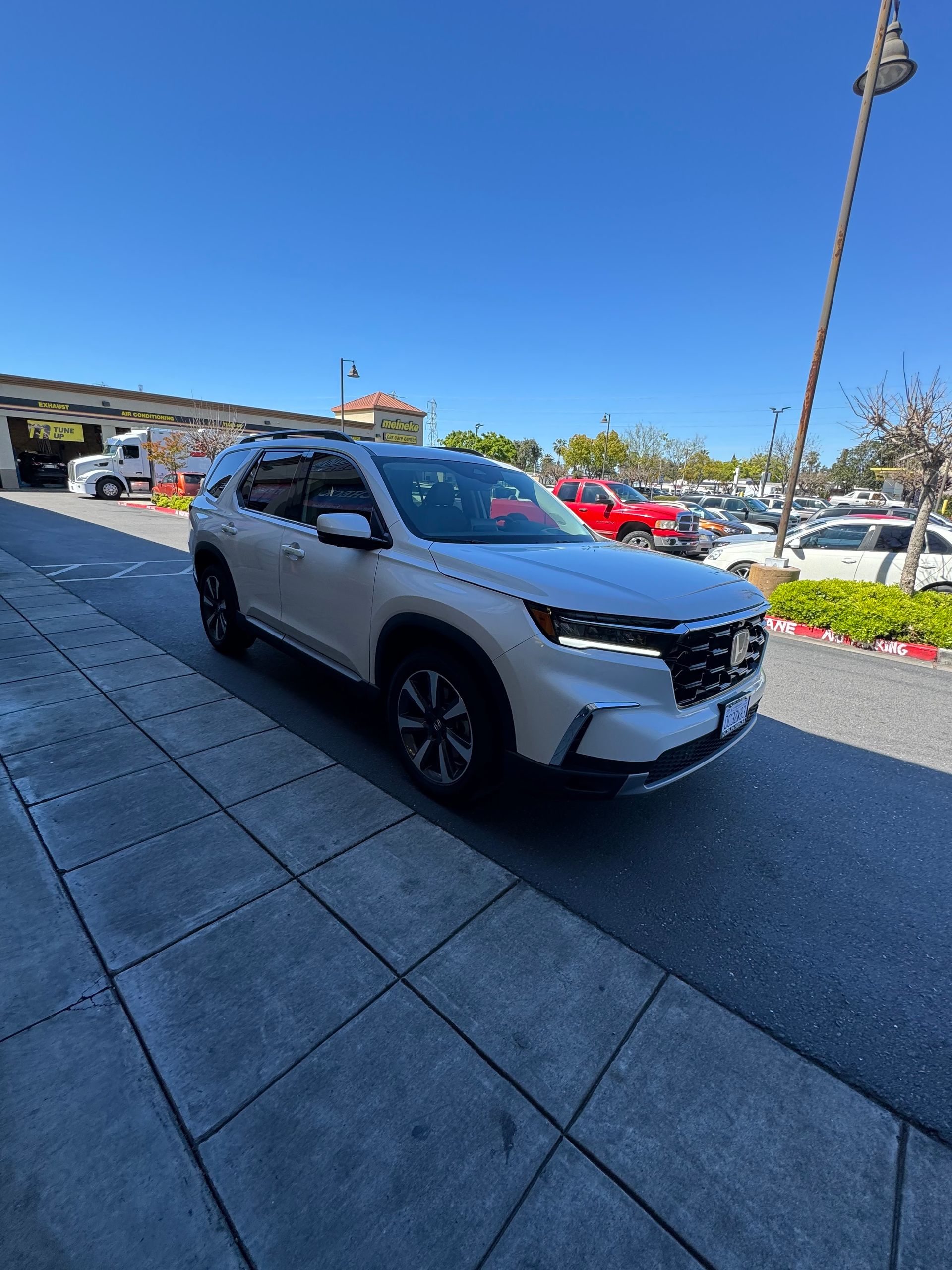 White SUV parked outside a building on a sunny day, with other cars in the background.