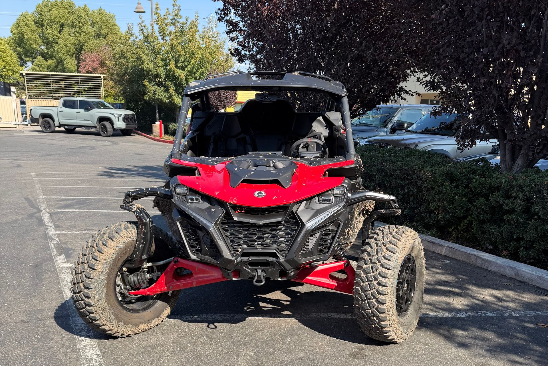 Red and black off-road UTV parked in a lot, viewed from the front.