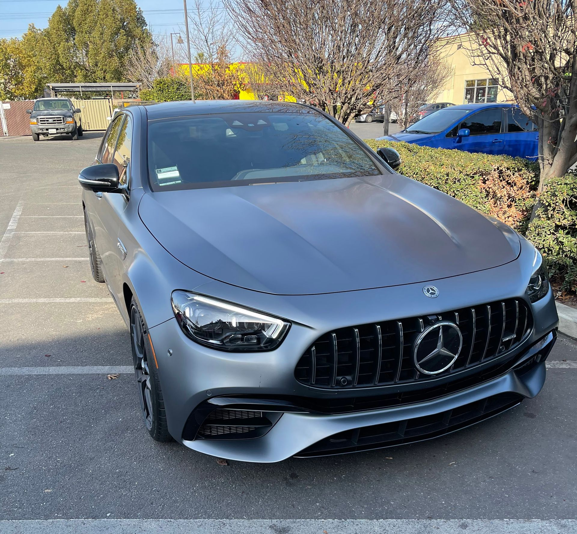 Gray Mercedes sedan parked in a lot with trees and other cars in the background