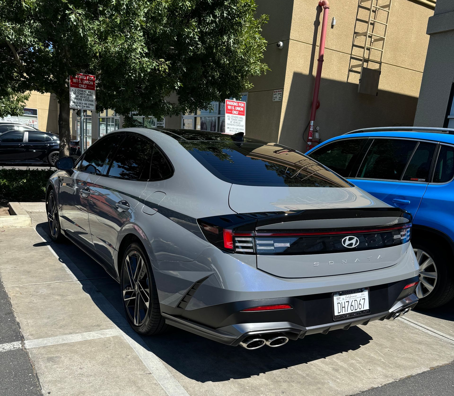 Silver Hyundai sedan parked on a sunny street next to a blue car.