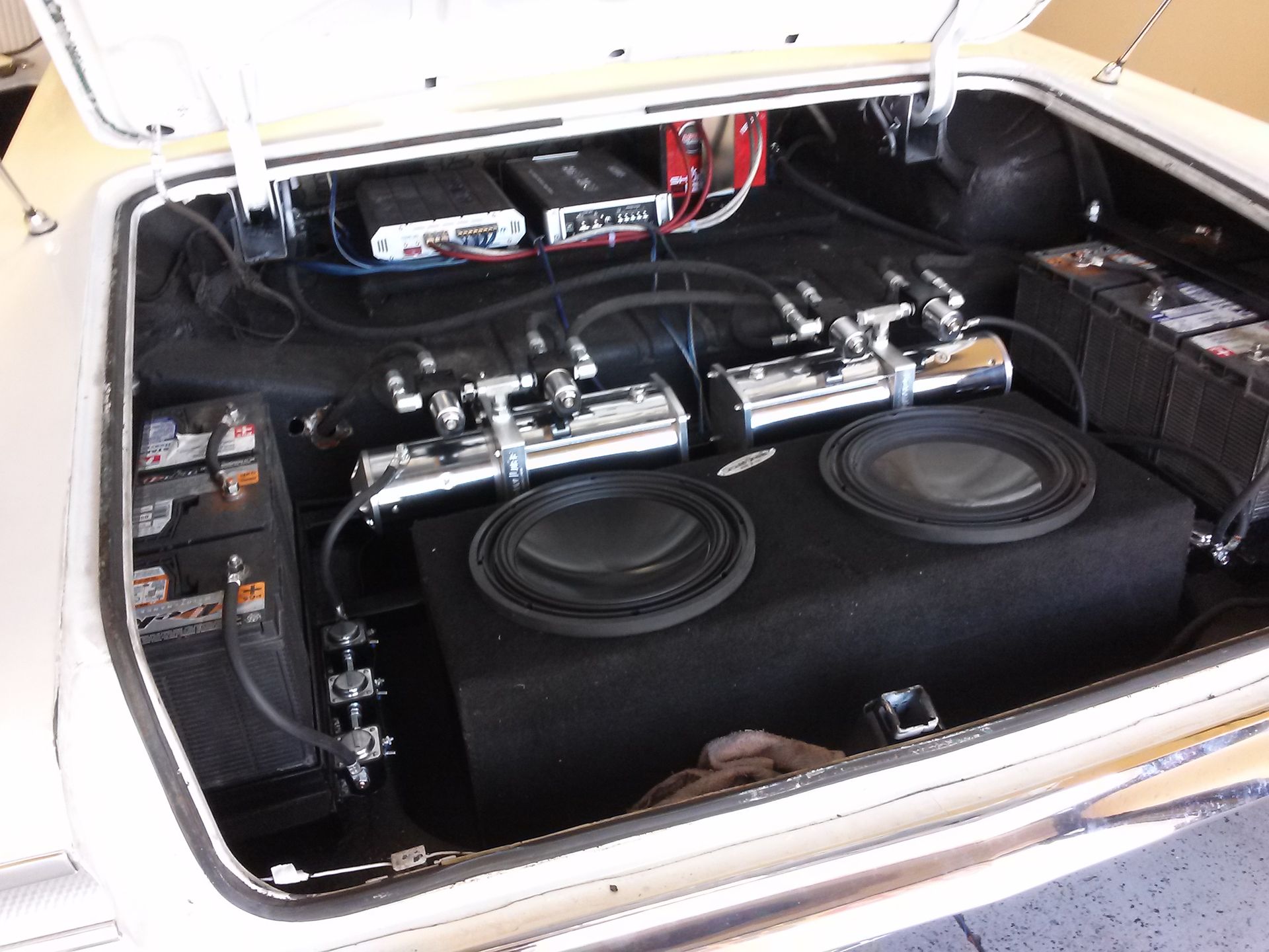 Car trunk with two large subwoofers and audio equipment installed in black carpeting
