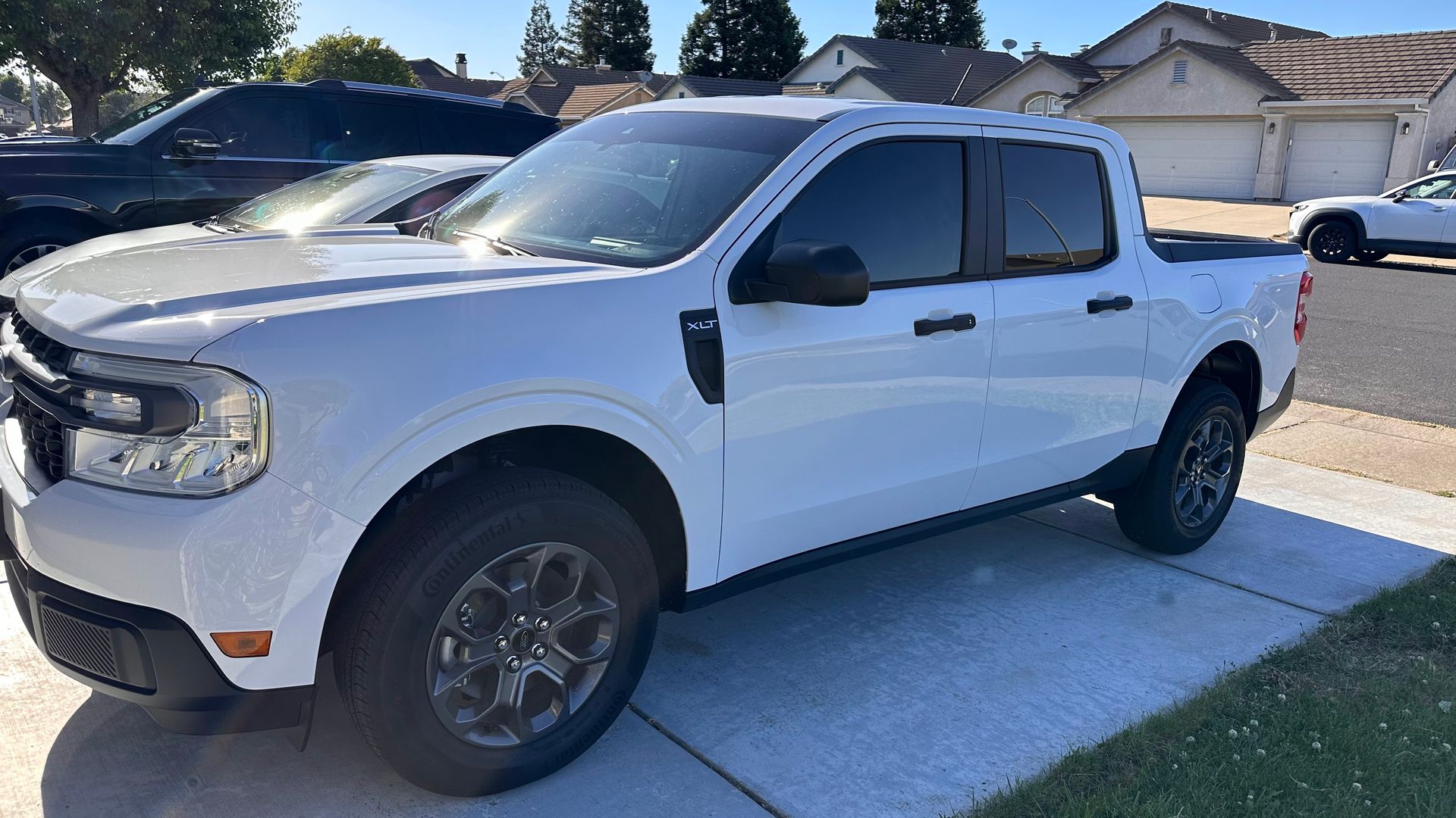 White pickup truck parked in a residential driveway on a sunny day.