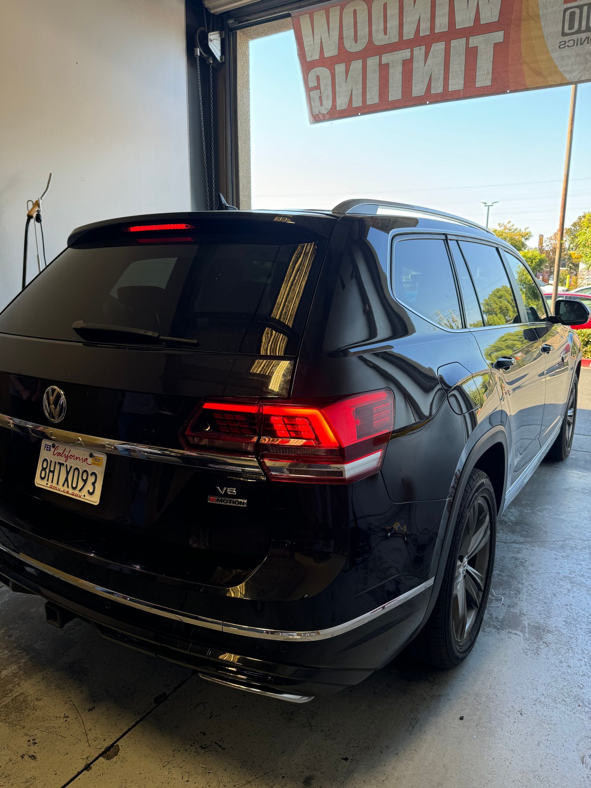 Black SUV parked in a garage, rear three-quarter view with red taillights and a reflective finish.