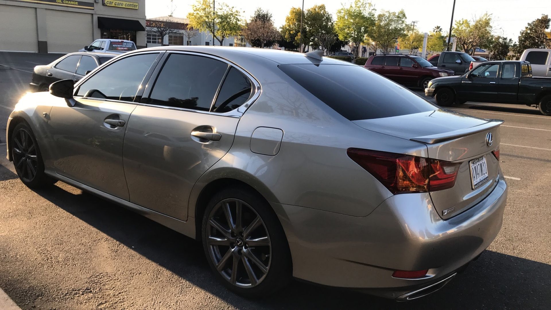 Silver sedan parked in a lot, rear three-quarter view at sunset.