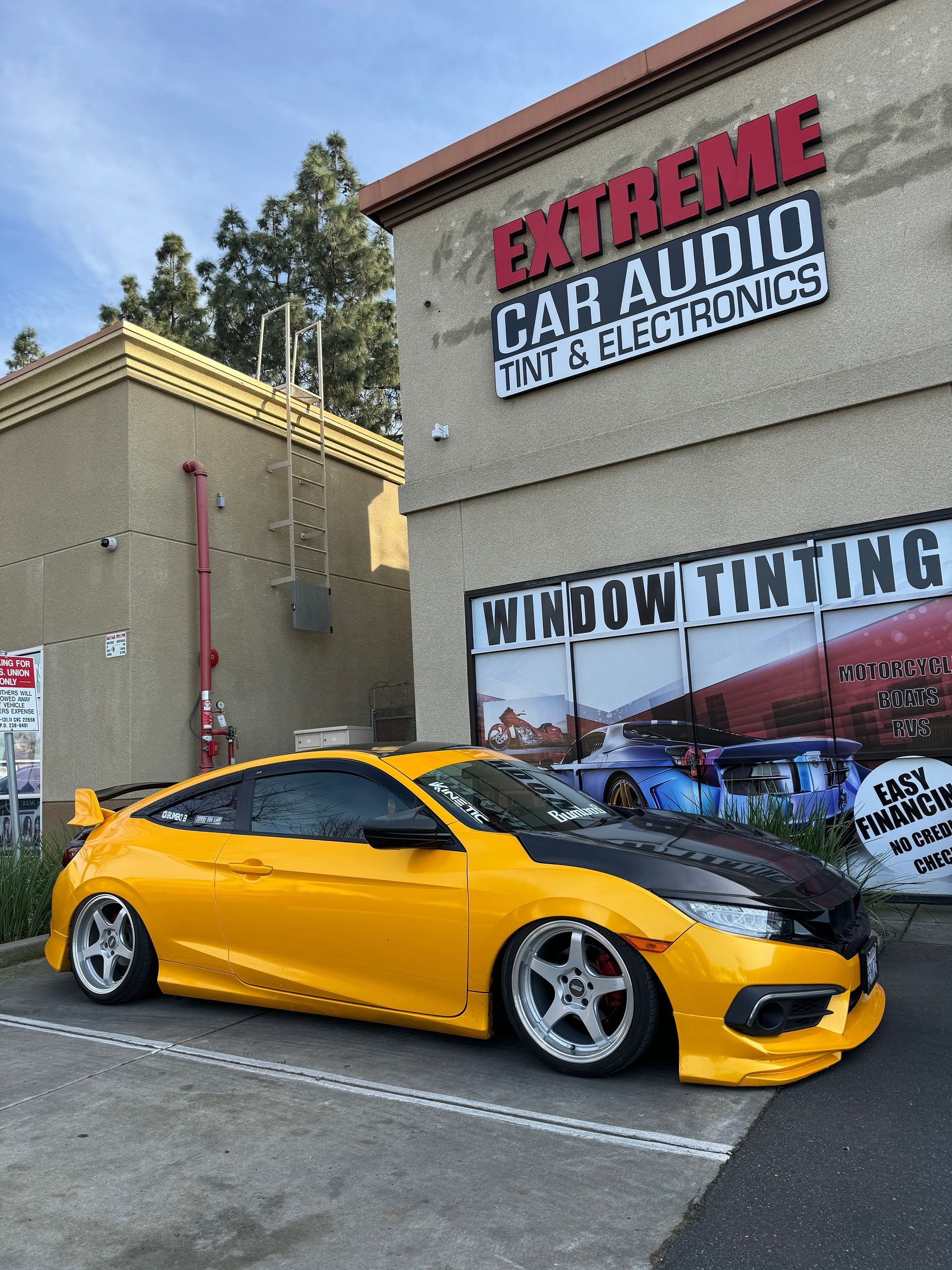 Yellow sports car parked outside Extreme Car Audio and custom tinting shop