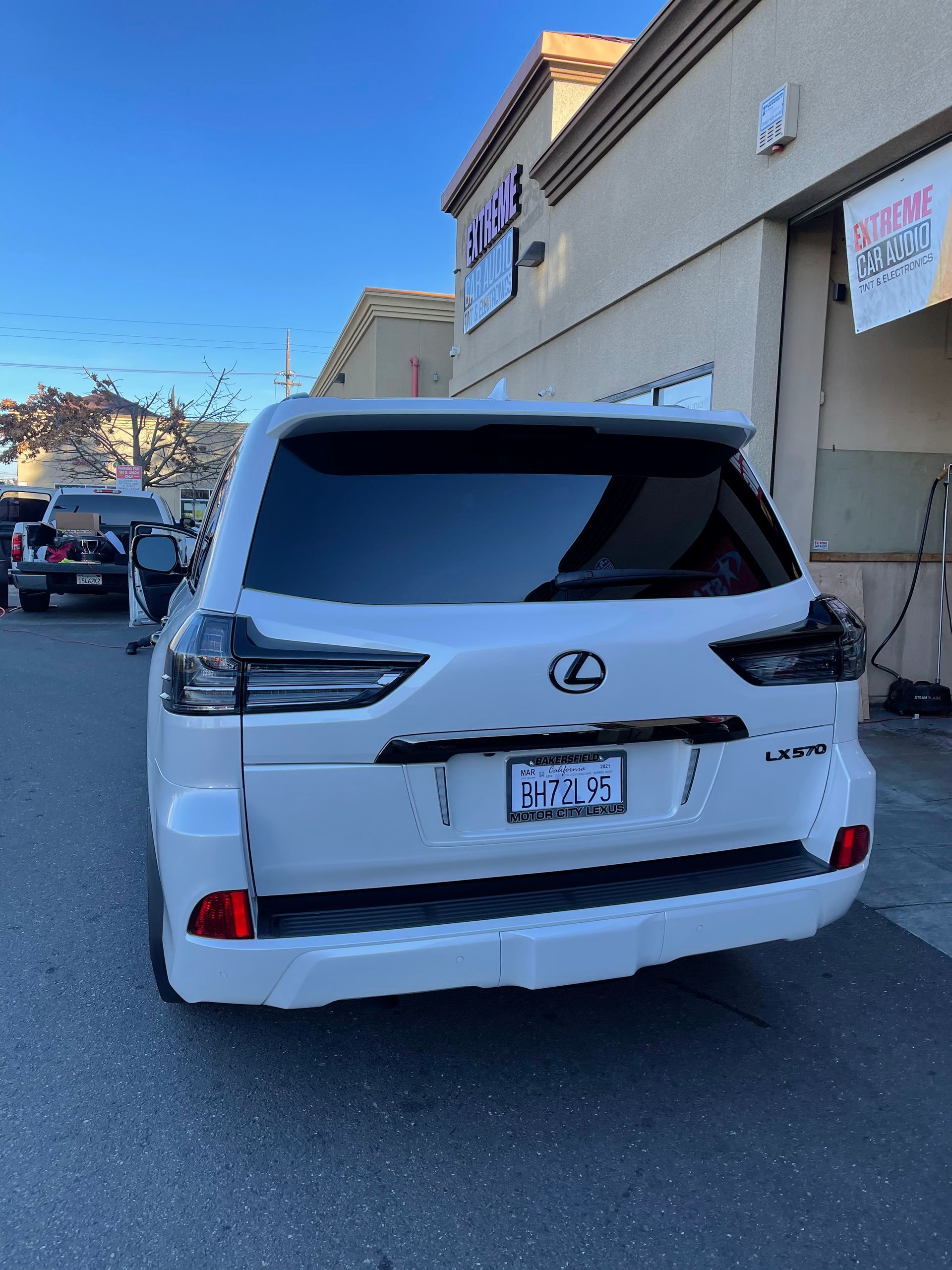 Rear view of a white Lexus SUV parked outside a beige building in a parking lot.