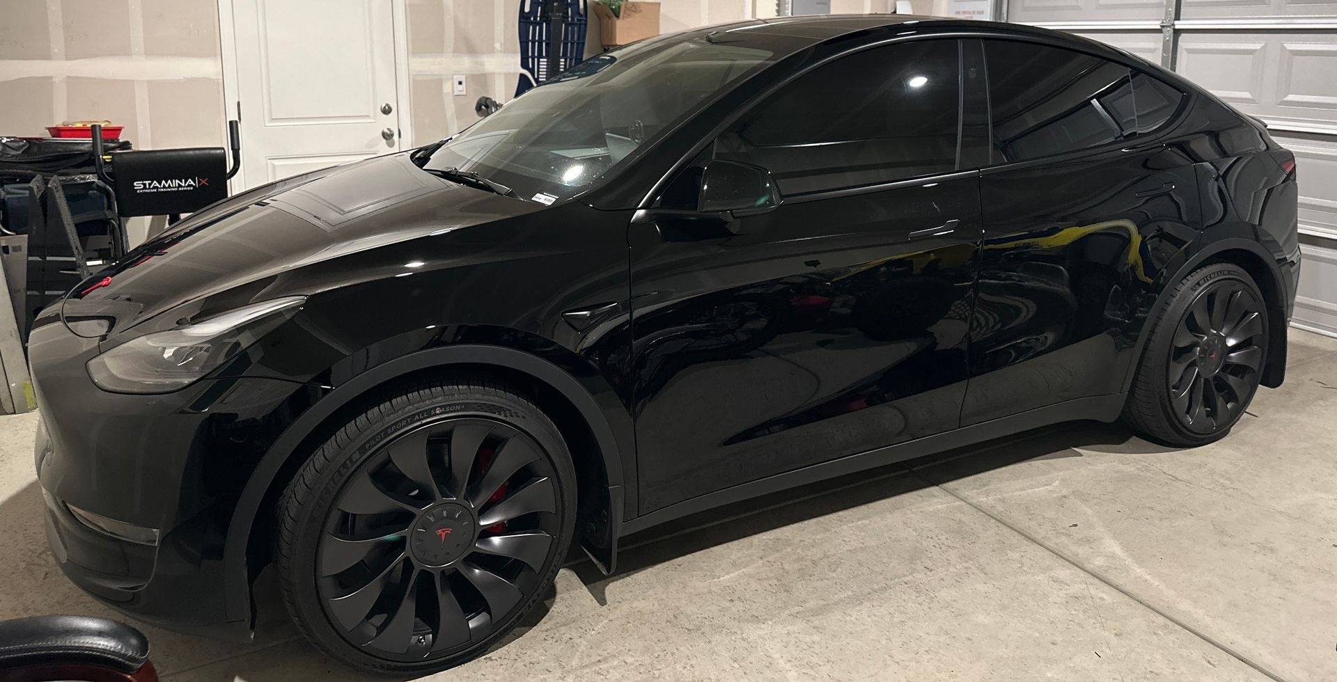 Black Tesla-style sedan parked in a garage, with tinted windows and black wheels