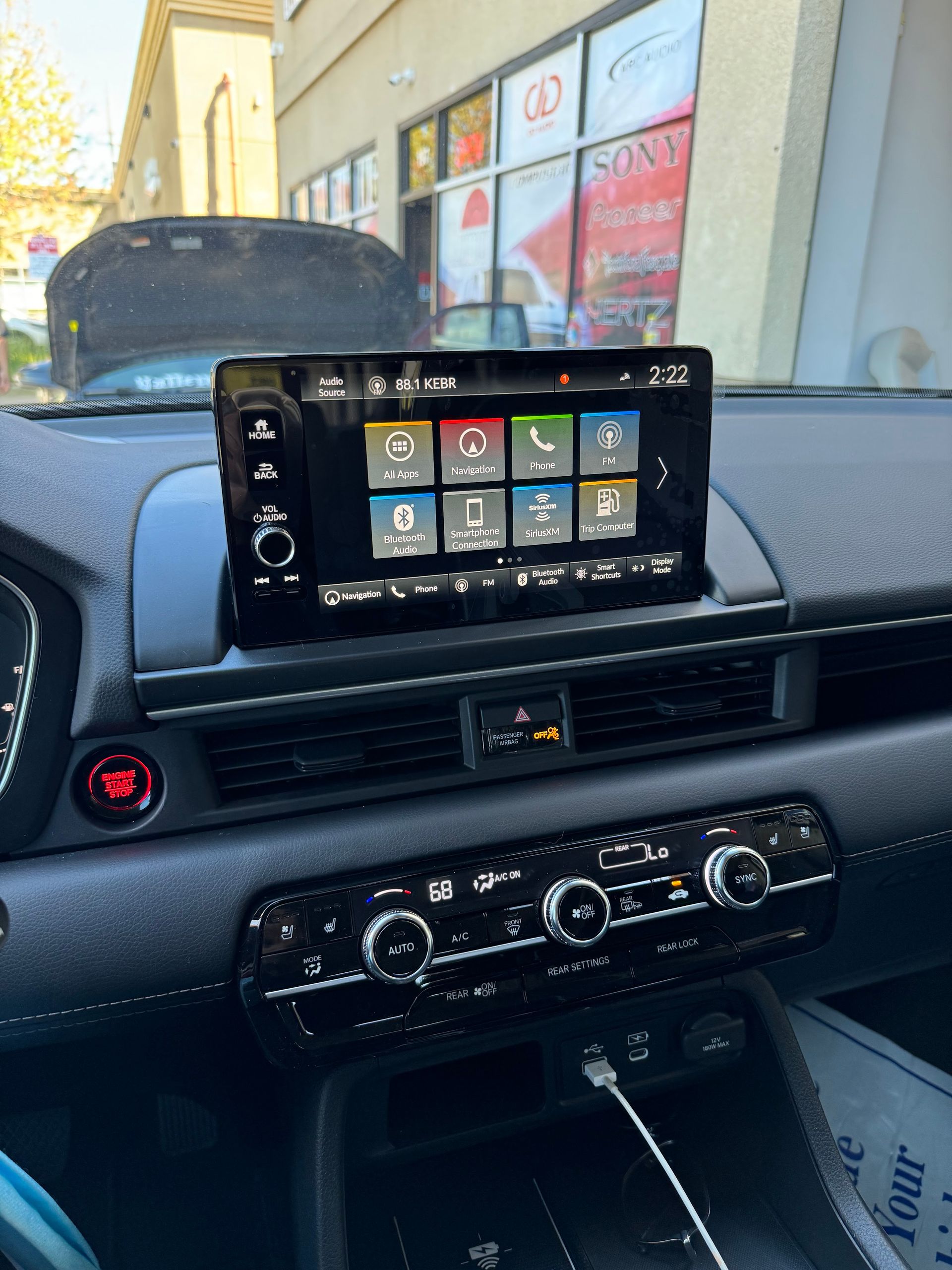 Car dashboard with a mounted touchscreen display showing app icons and climate controls below.