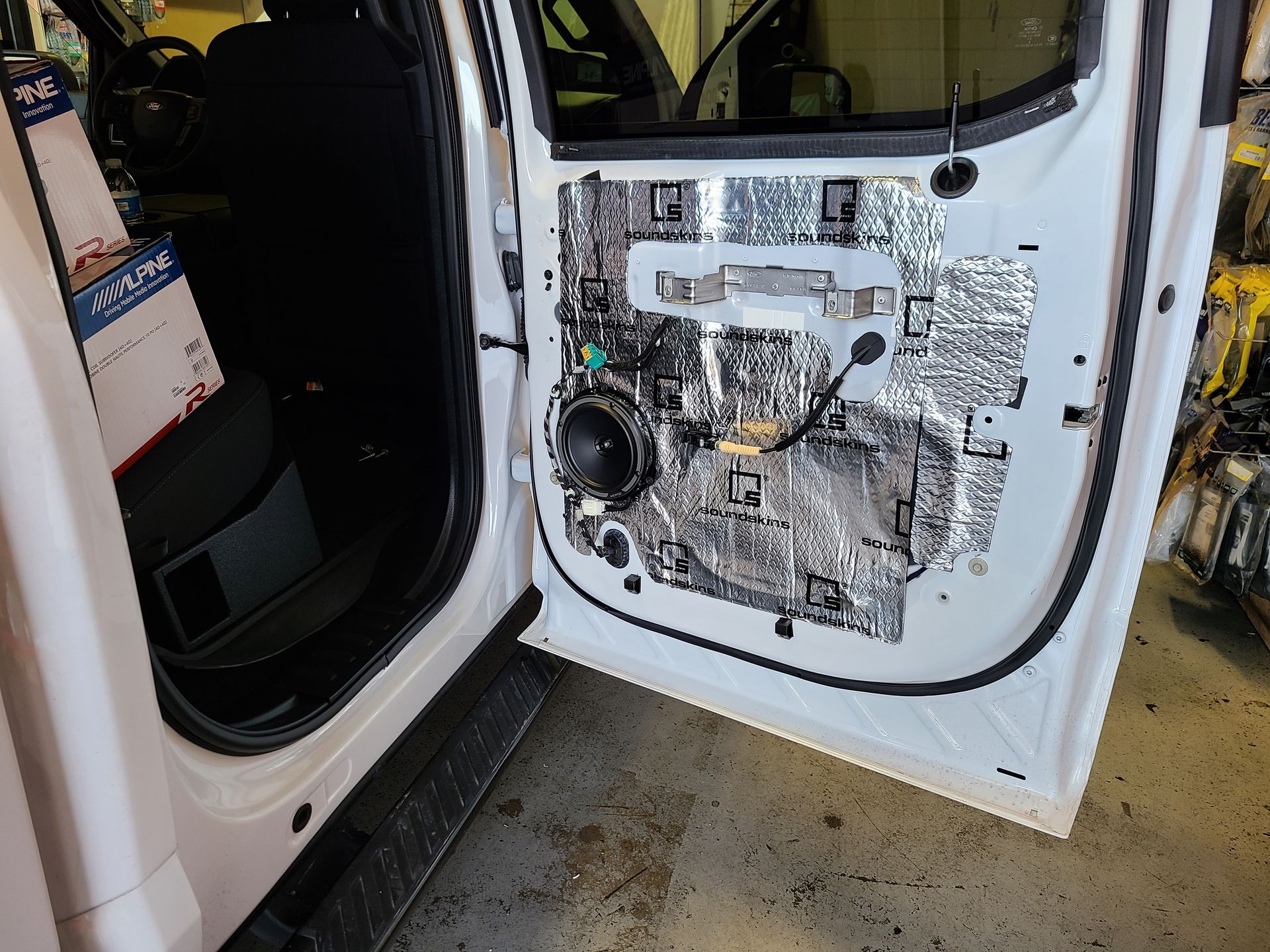 Car door interior panel removed, exposing wiring and mechanisms inside a white vehicle.