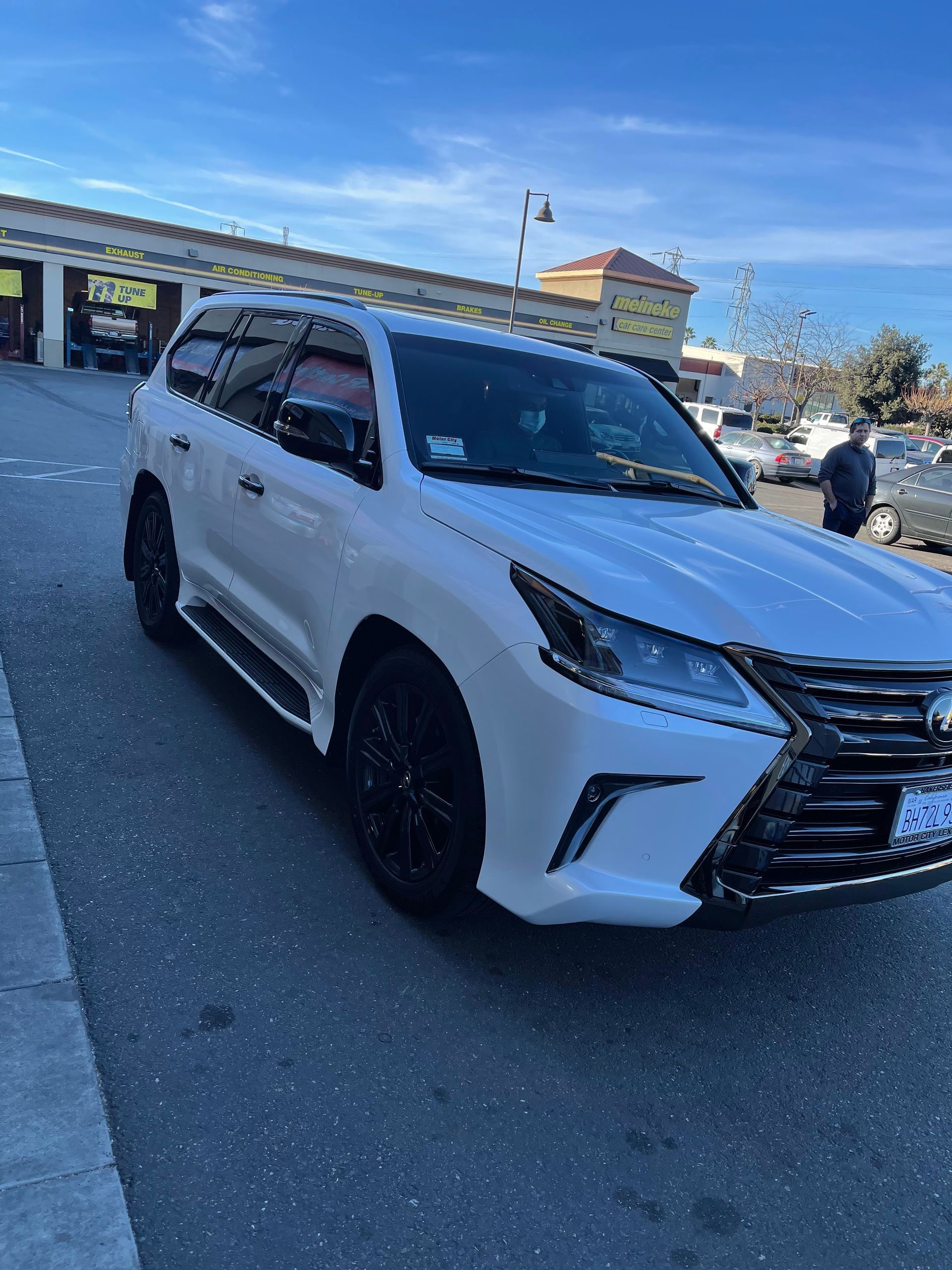 White SUV parked in a lot, angled front view on a sunny day