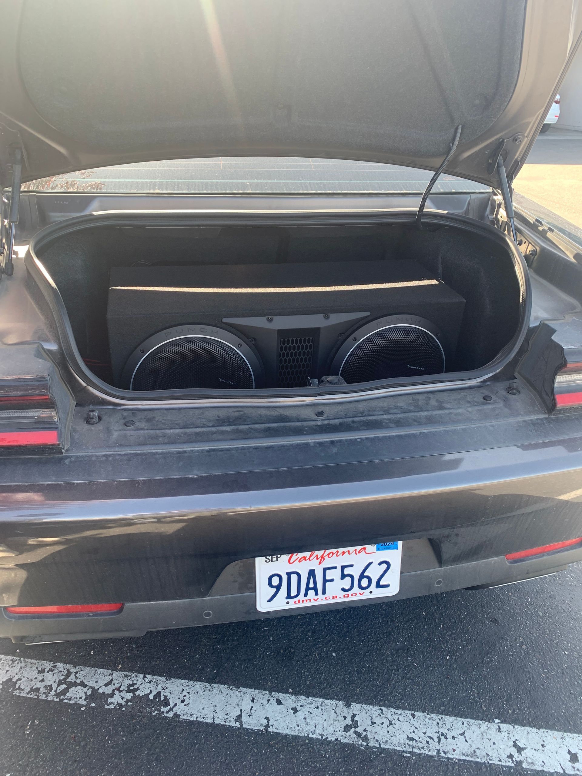 Open car trunk with two black speakers installed in the cargo area.