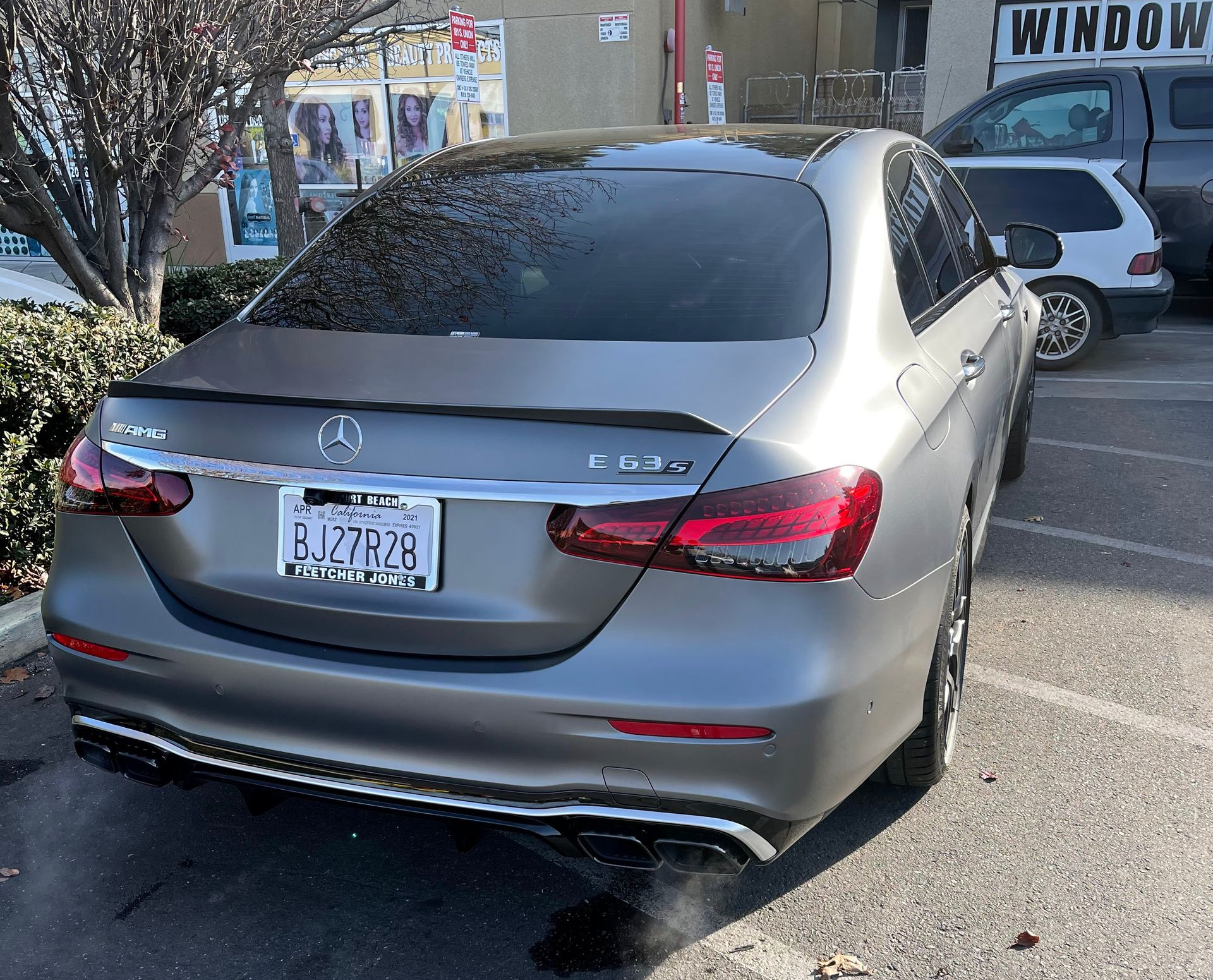 Silver Mercedes sedan parked on a street, rear view with tinted windows and visible license plate.