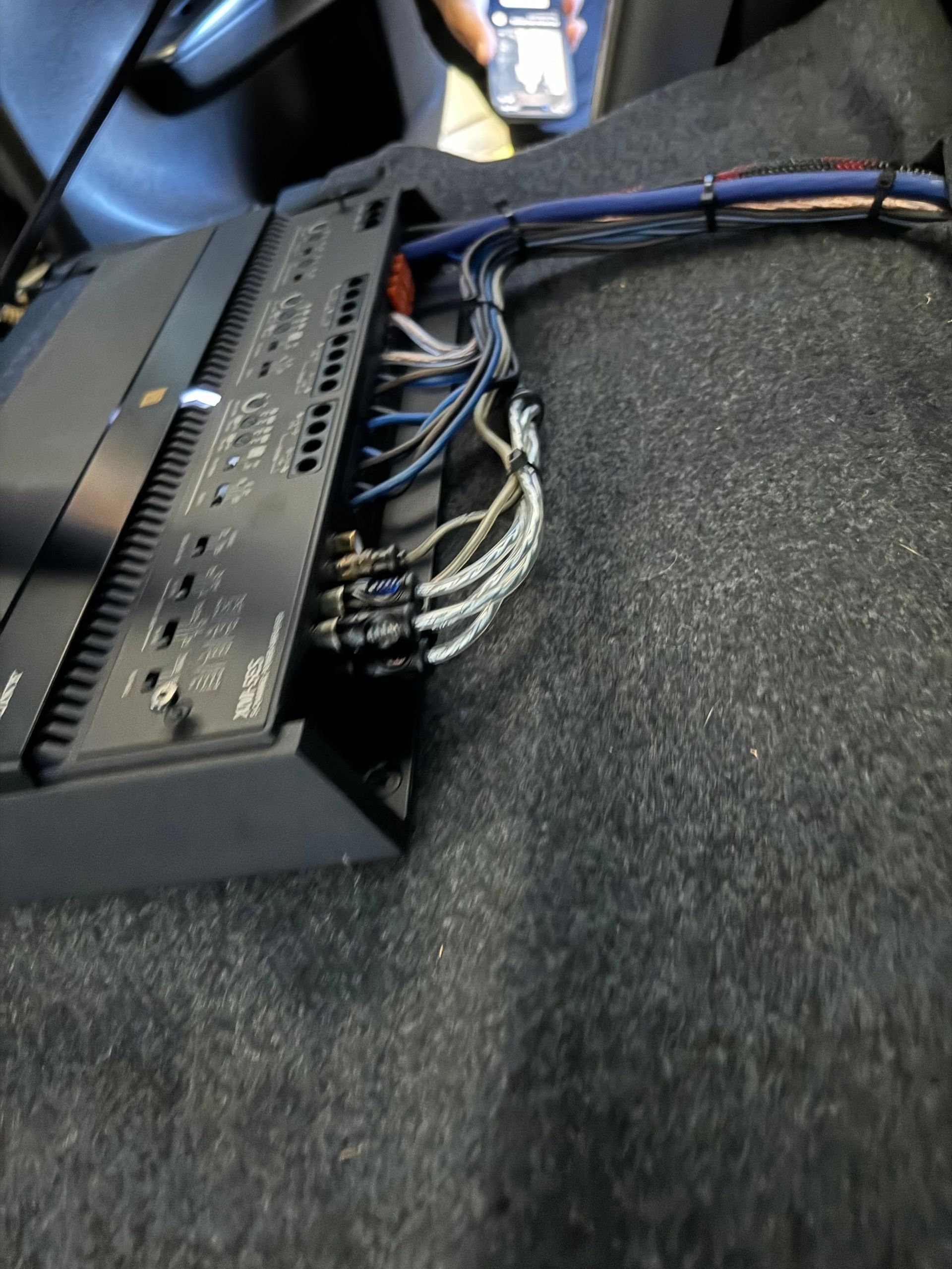 Wiring bundle plugged into a black electronic device on carpet, with cables and connectors visible