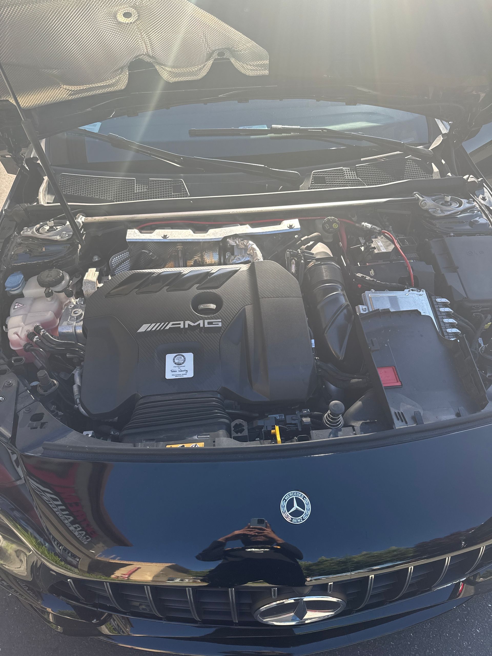 Open car hood showing a SYNCRO engine bay on a dark blue vehicle outdoors.