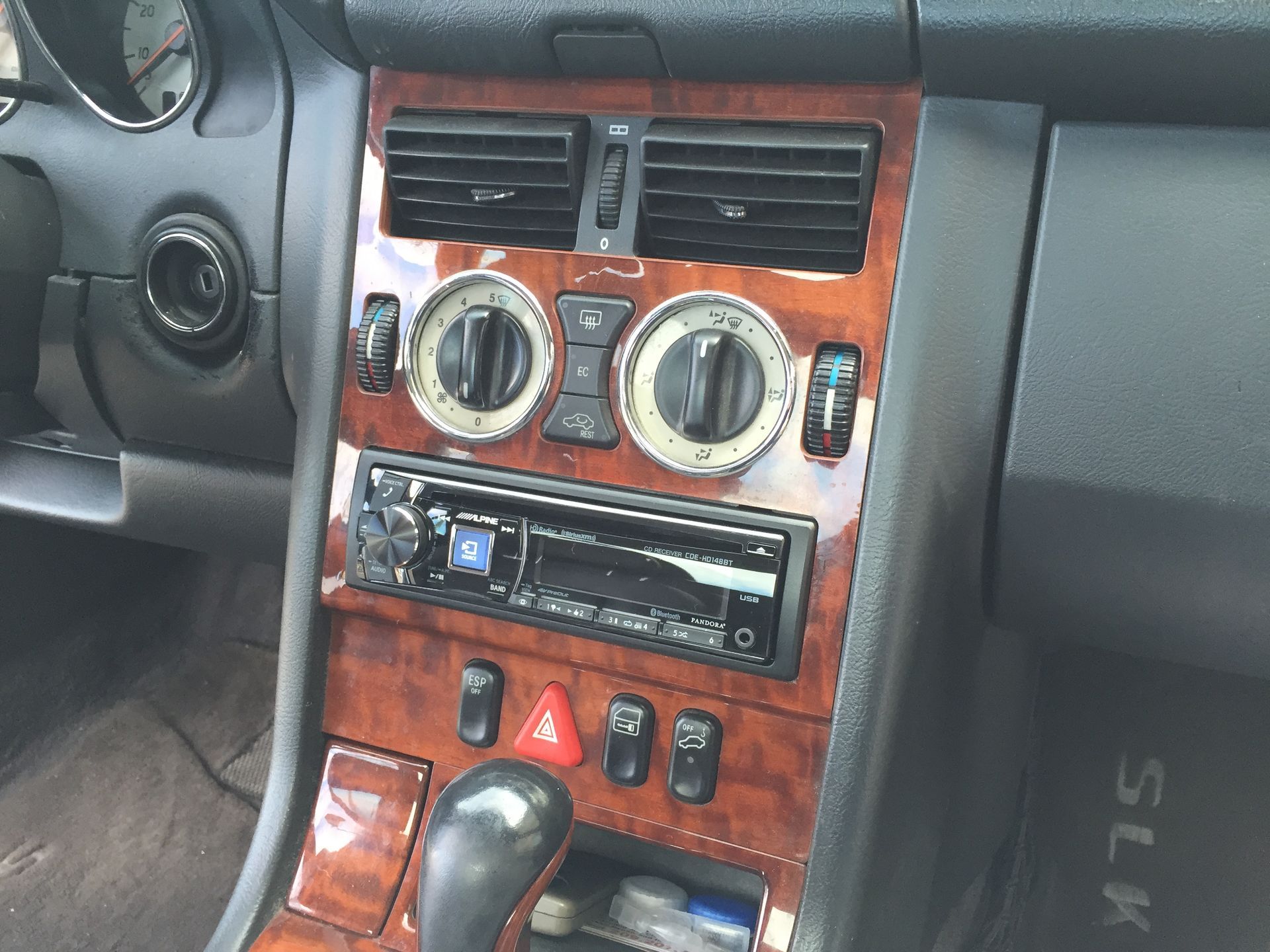 Car interior center console with wood trim, air vents, climate knobs, stereo, and gear shift knob.