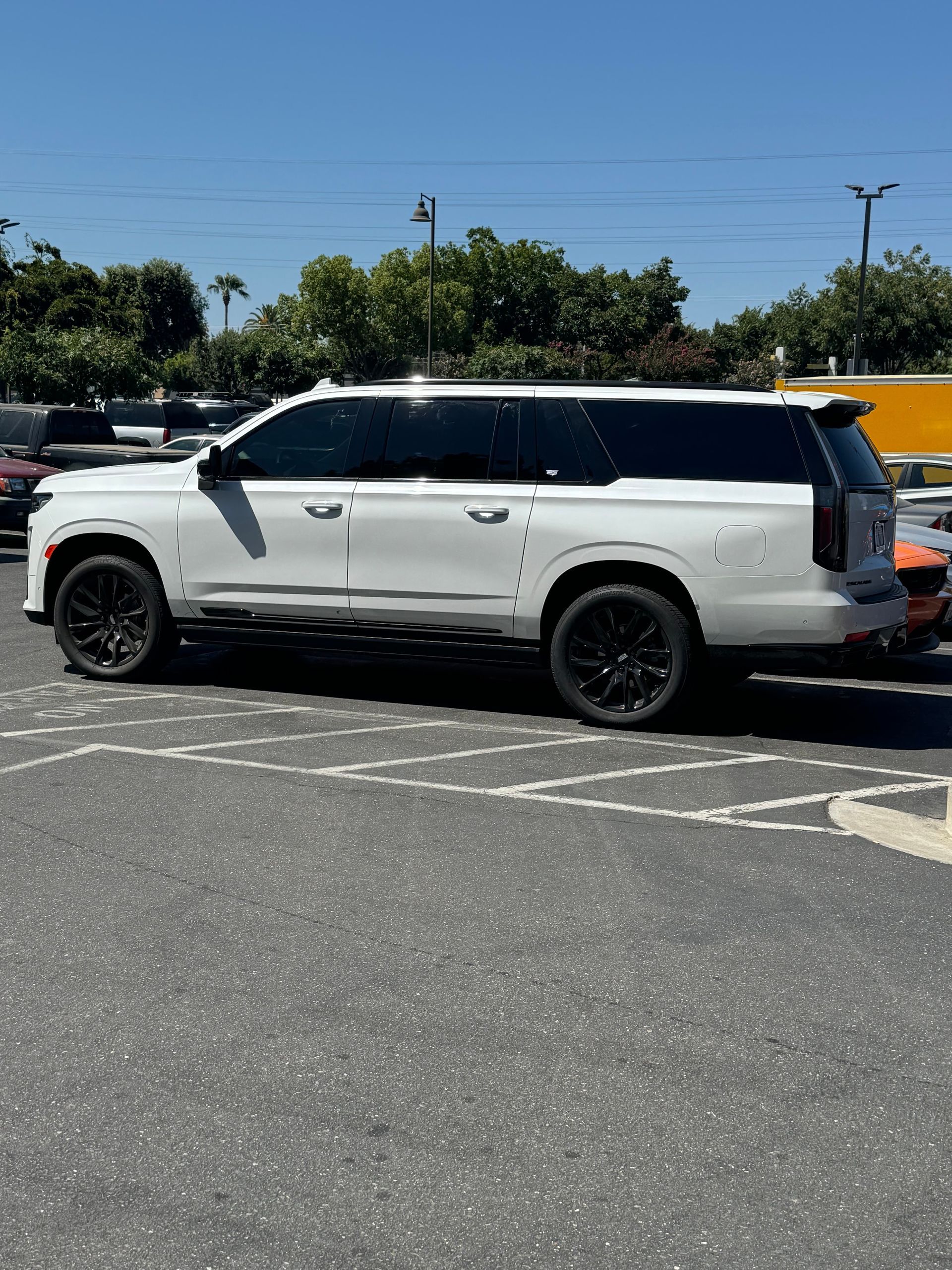White SUV parked in a lot under a bright blue sky, side view
