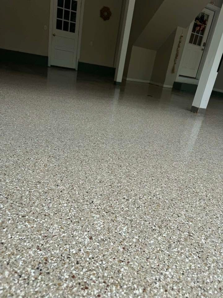 Empty garage with epoxy floor, black door, and a small window.