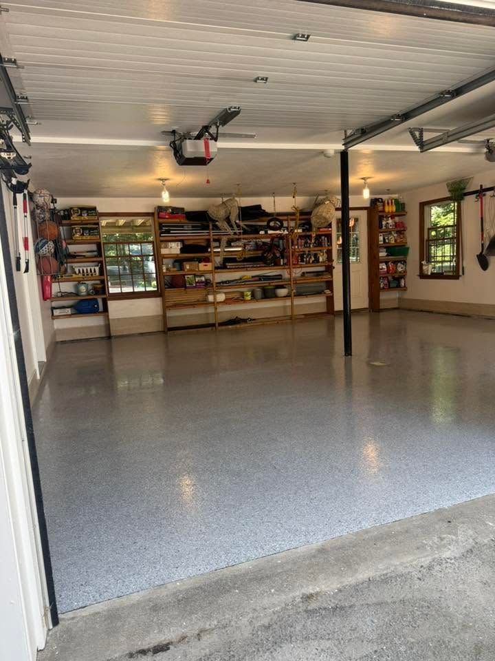 Close-up of a speckled, shiny garage floor with a car visible in the open garage door.
