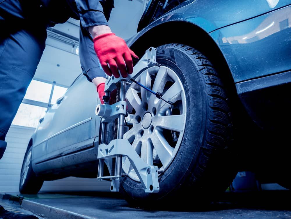 A Technician in Red Gloves Attaches a Wheel Alignment Sensor — Berkeley Vale Tyre & Mechanical in Fountaindale, NSW