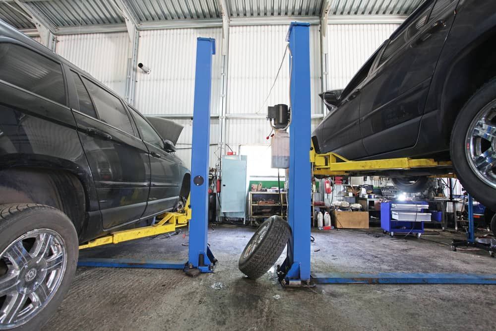 Two Black Cars Lifted on Blue Hydraulic Service — Berkeley Vale Tyre & Mechanical in Fountaindale, NSW