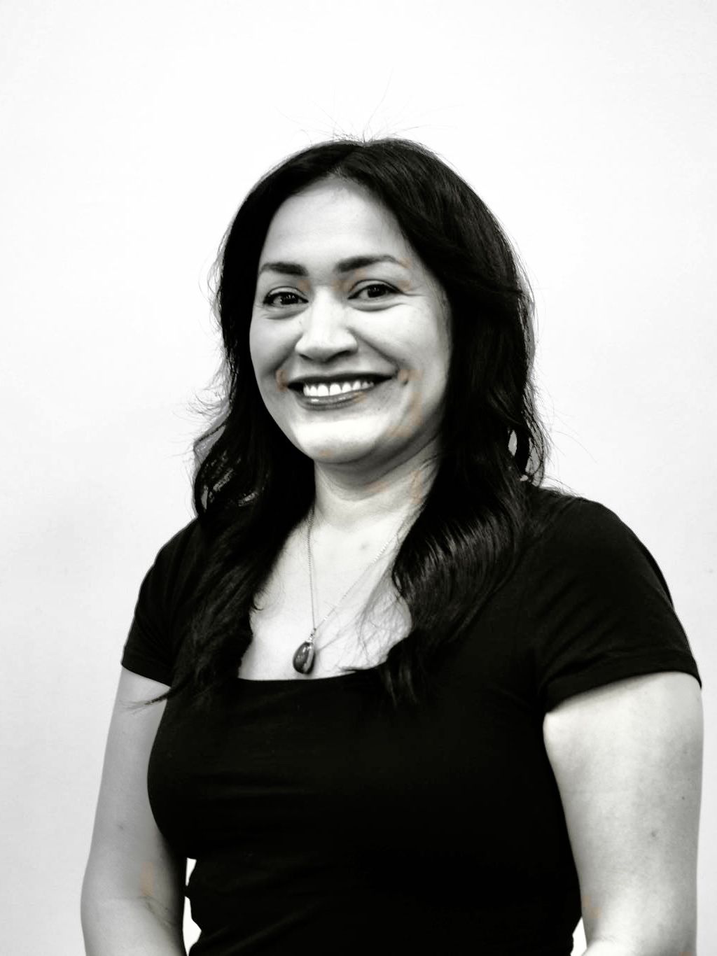 Smiling woman with curly hair in a black top against a plain background