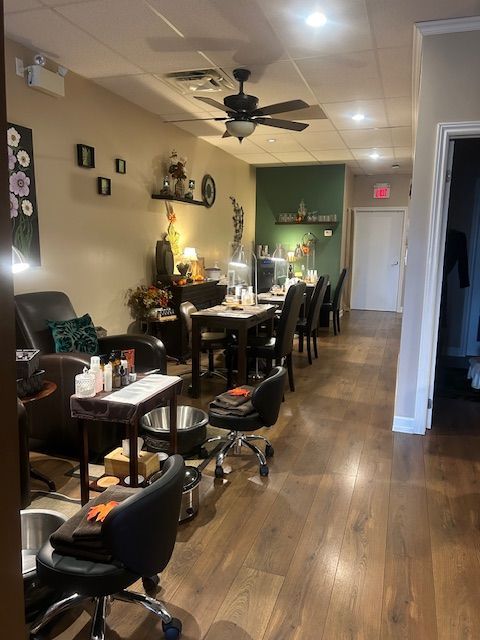 Nail salon interior with manicure stations, pedicure chairs, and decor. Wood floors and neutral walls.