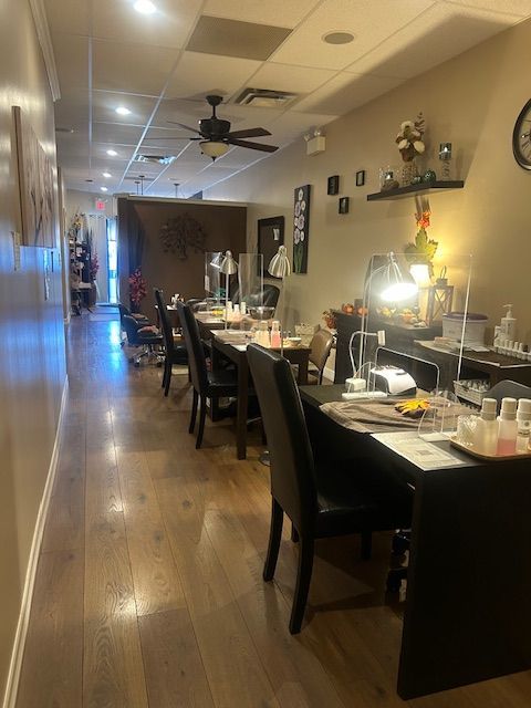 Nail salon interior with manicure stations, chairs, and lamps. Wooden floor and beige walls.