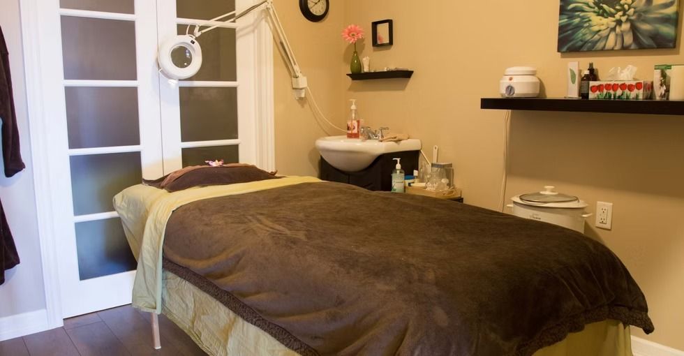 Massage therapy room with bed, sink, and decorative items; warm color palette.
